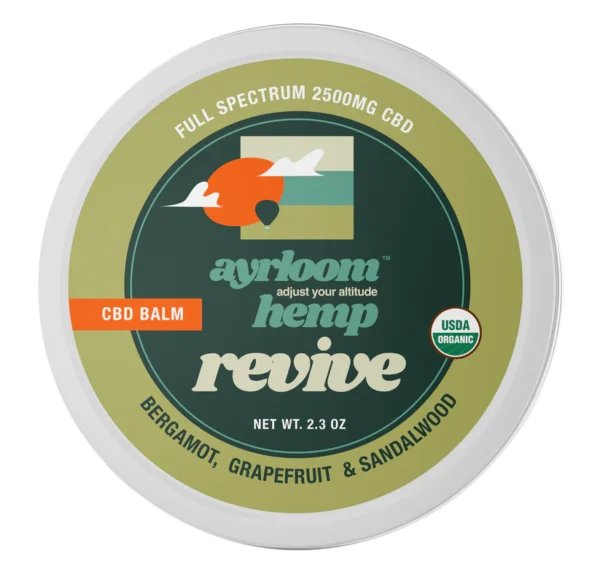 A small container of Ayrloom Revive Balm with bright citrus and earthy branding, highlighting bergamot, grapefruit, and sandalwood.